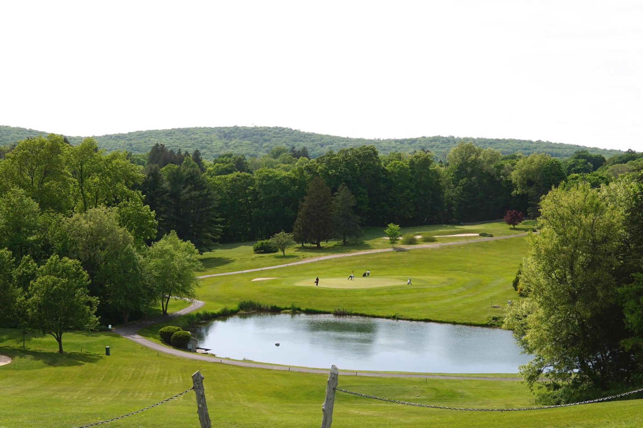 From high on the fifth fairway, a long look down at green seven, where a threesome is putting out. (Photo submitted by AptlyLinked on 05/20/2023)