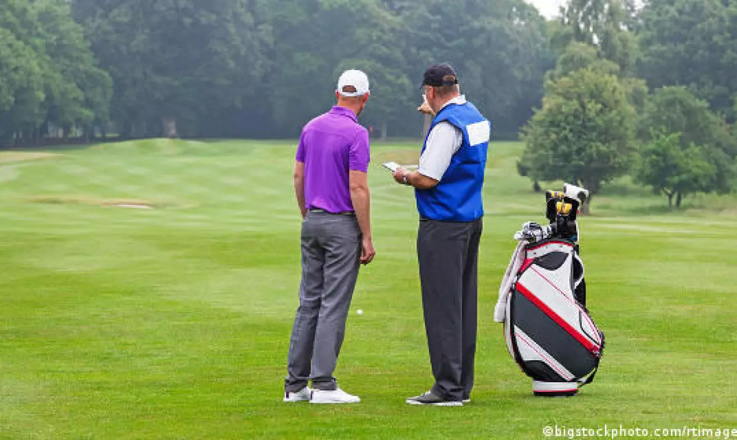 Caddy pointing out a hazard to the golfer on a par 4 fairway