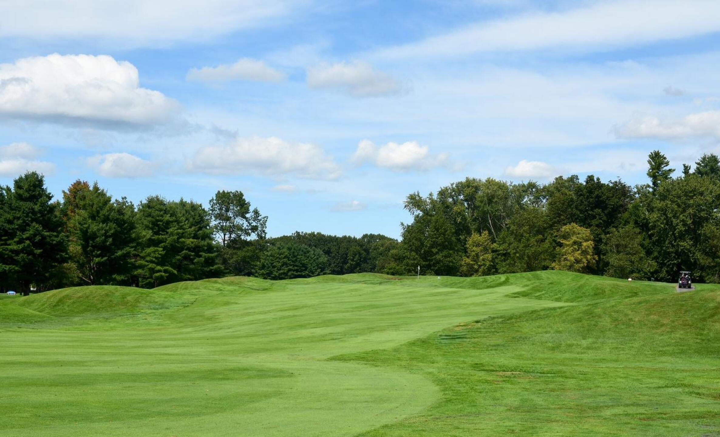 Hole 5 seems to reference classic Scottish golf as you approach the hole. There is the mounding, the wriggling fairway, a green that lies atop a long rise, and behind it two bunkers–hidden from view. (Photo submitted by AptlyLinked on 09/15/2025)