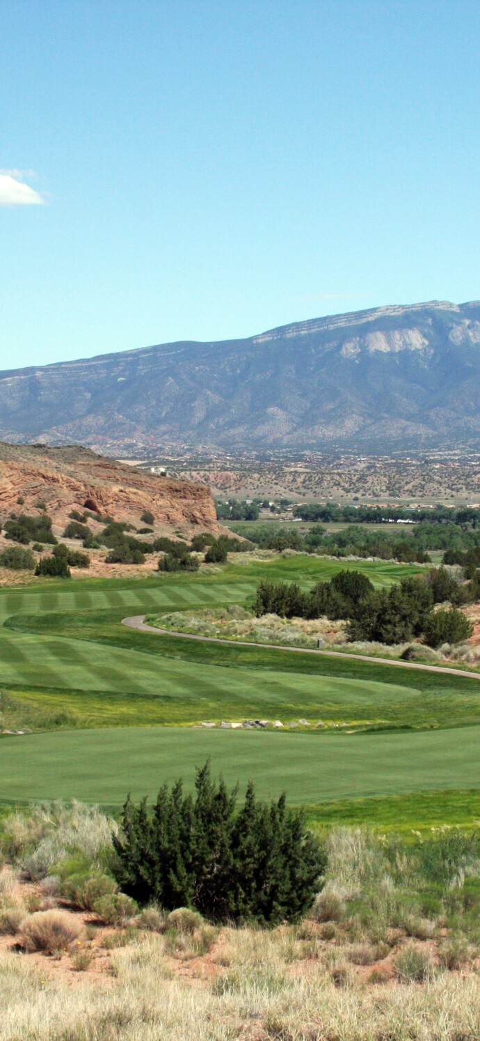 Image of golf course with mountains in the background on a sunny day