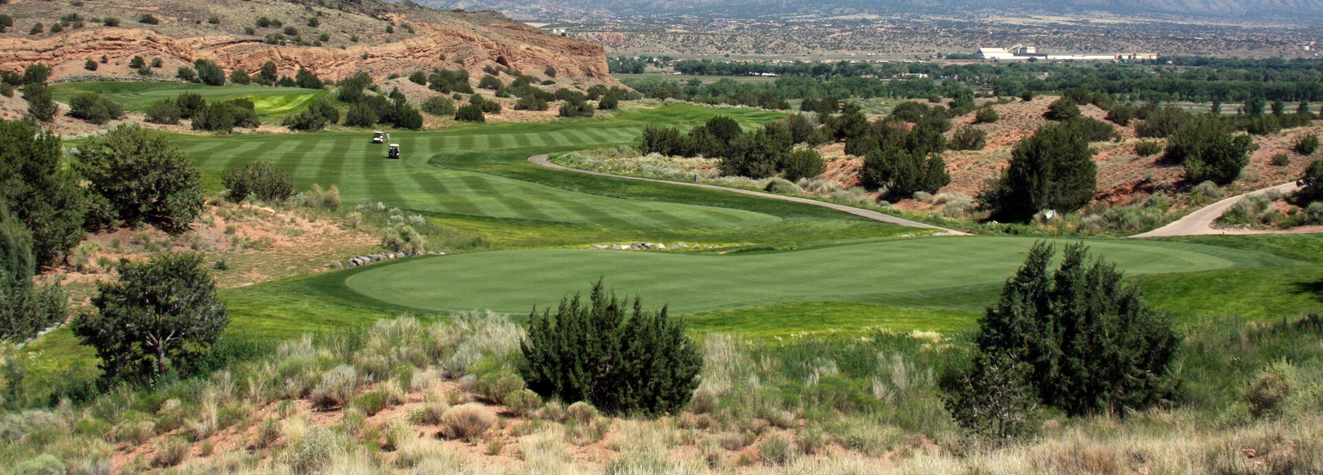 Image of golf course with mountains in the background on a sunny day